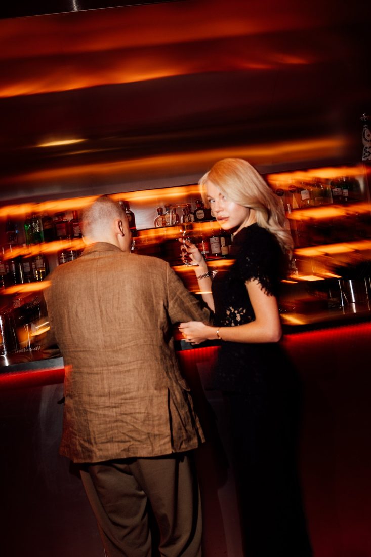 Guest at the bar glancing back, warm motion-blurred light