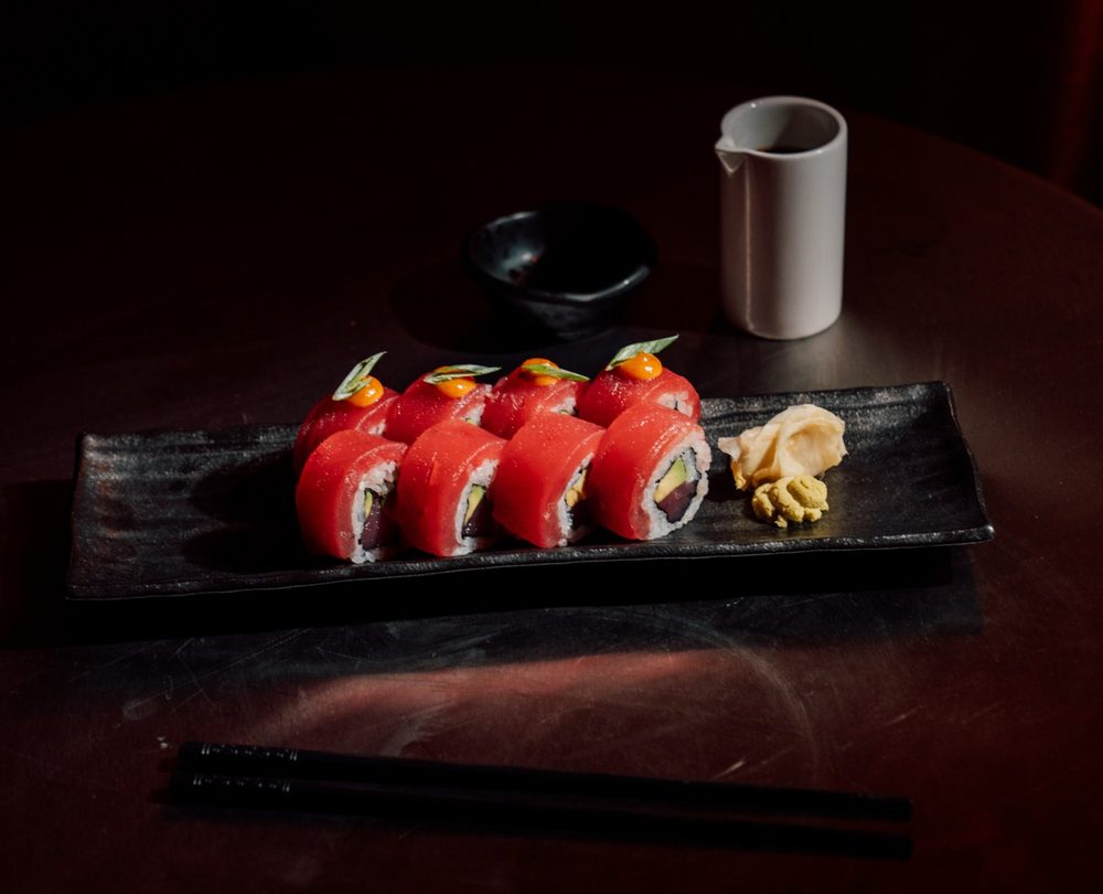 Tuna maki with ginger and wasabi on a black plate